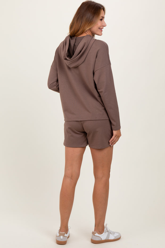 woman wearing a brown hoodie with shorts, showing the back view and paired with white sneakers