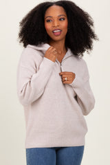 woman wearing a light beige half-zip knit sweater with a relaxed fit and long sleeves, smiling at the camera