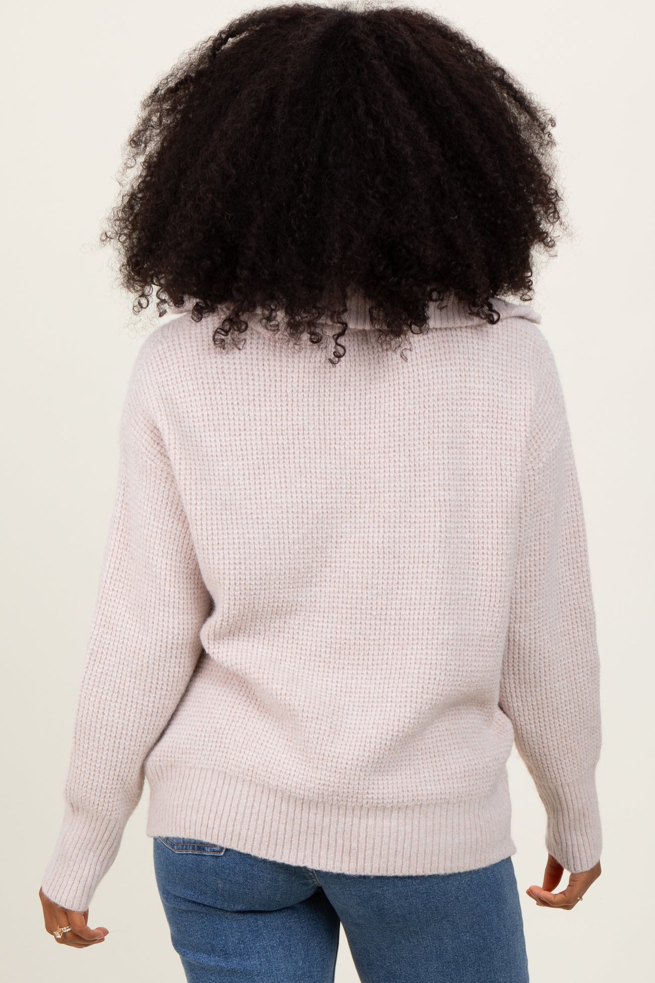woman wearing a light pink oversized knit sweater with a cozy turtleneck and cuffed sleeves