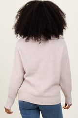 woman wearing a light pink oversized knit sweater with a cozy turtleneck and cuffed sleeves