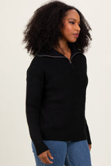 woman wearing a black zip-up sweater with a high collar and long sleeves, styled with blue jeans