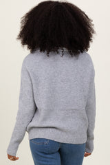 woman wearing a cozy gray knitted sweater with a relaxed fit and ribbed hem, viewed from the back