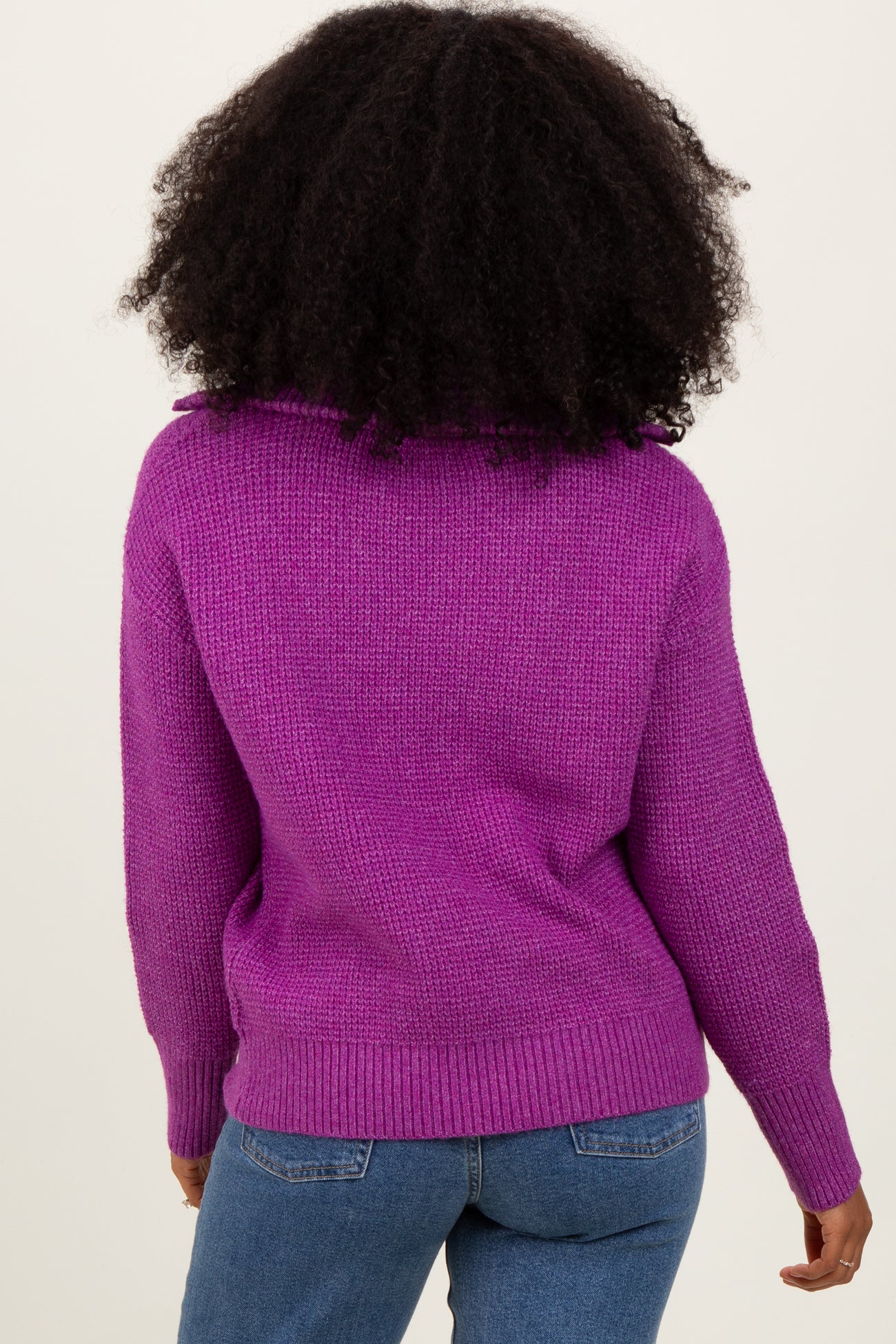 woman wearing a purple cozy knitted sweater with a relaxed fit and a ribbed hem, seen from the back