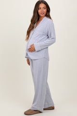 woman wearing a light gray maternity pajama set with a button-up top and loose pants, showing her baby bump