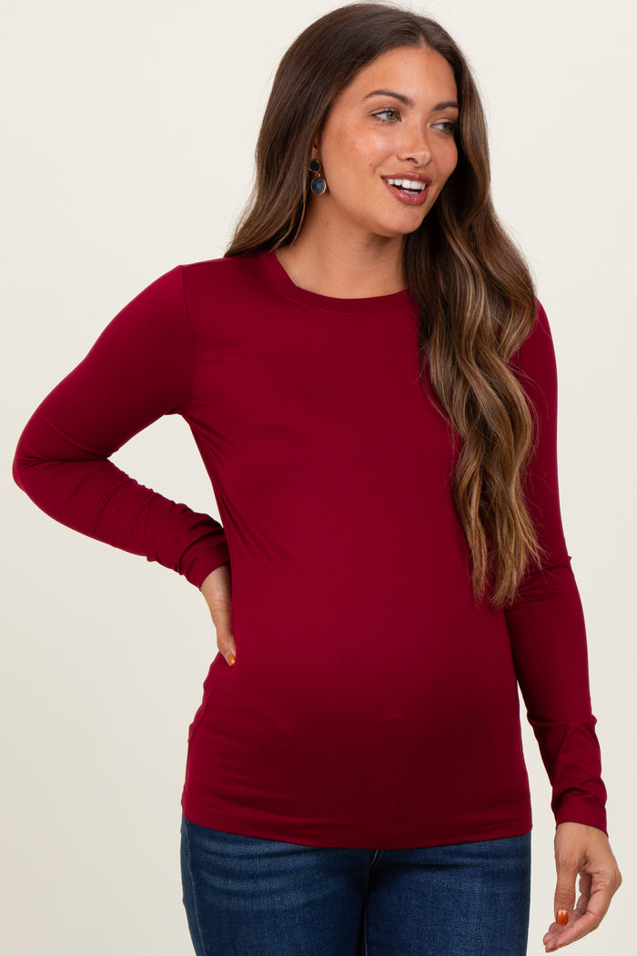 woman wearing a burgundy long sleeve maternity top with a fitted style and visible baby bump