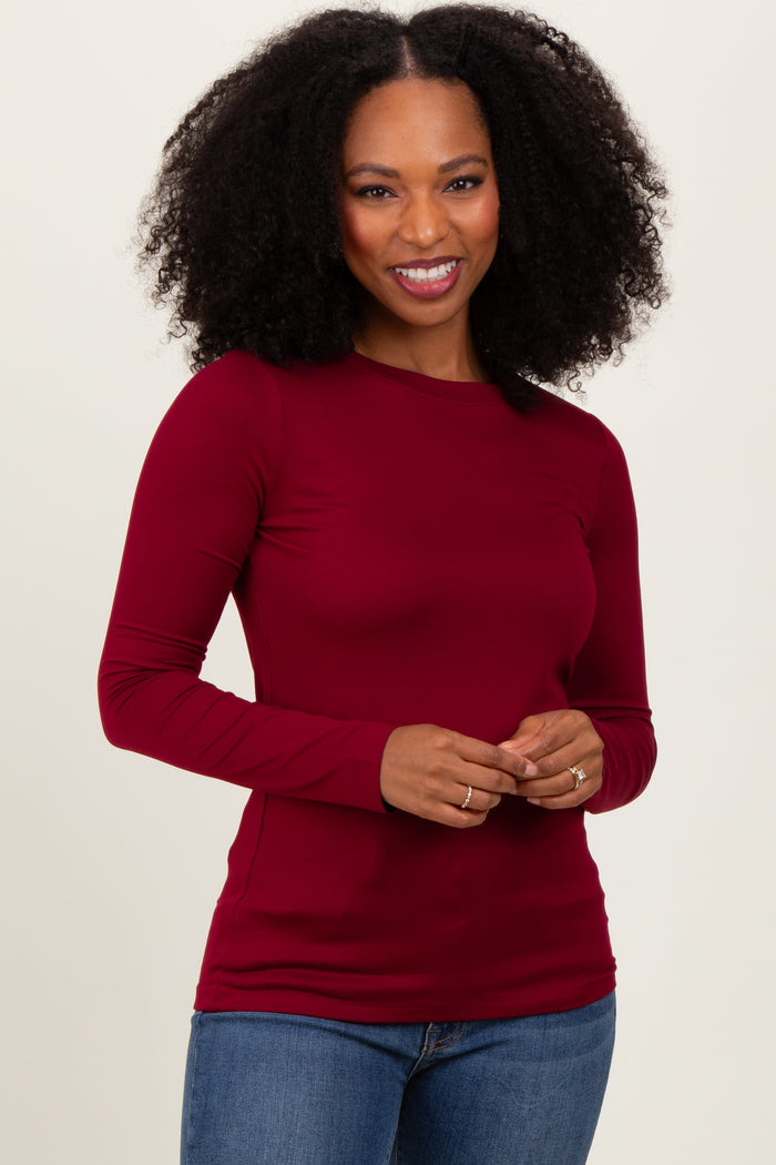 woman wearing a burgundy long sleeve fitted top and blue jeans