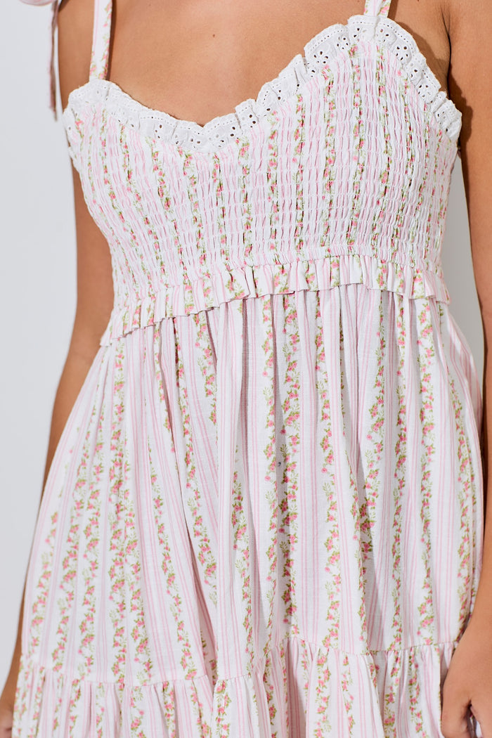 woman wearing a pink and white floral smocked maxi dress with lace trim and ruffled details