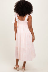 woman wearing a pink gingham midi dress with ruffled shoulder straps and smocked bodice, shown from the back