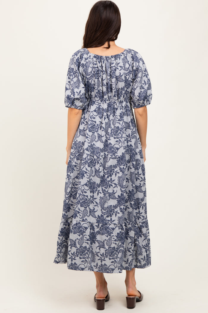 woman wearing a navy blue floral maxi dress with puff sleeves and a cinched waist, viewed from the back