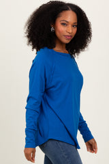 woman wearing a blue long sleeve relaxed fit top with side slits and a round neckline, styled with blue jeans