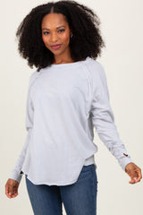 woman wearing a light gray long sleeve top with side slits and a relaxed fit, paired with blue jeans
