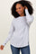 woman wearing a light gray long sleeve top with relaxed fit and side slit details, paired with blue jeans