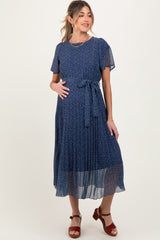 woman wearing a dark blue floral maternity dress with short sleeves and a tie belt, showing her baby bump