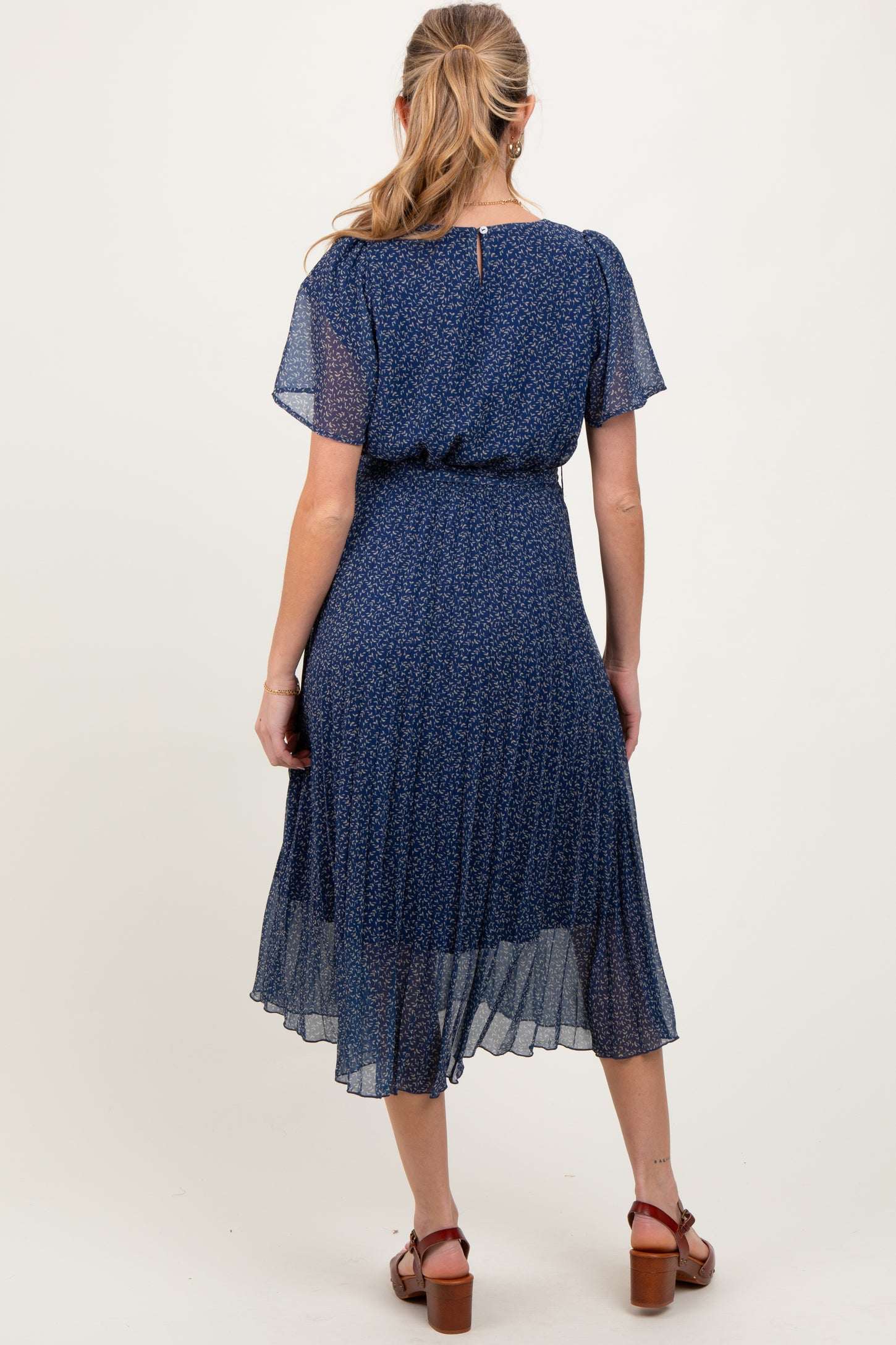woman wearing a navy blue floral maternity dress with short sleeves and flowing skirt, showing a baby bump from the back