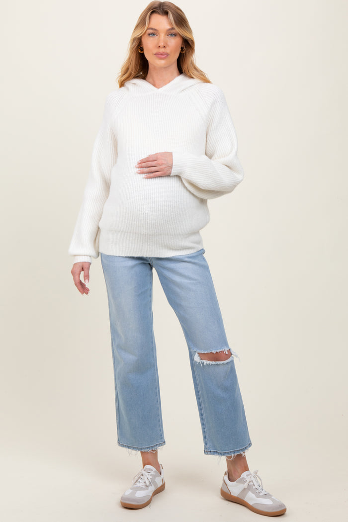 woman wearing a white ribbed maternity hoodie and blue distressed jeans, holding her baby bump