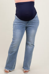 woman wearing light blue maternity plus jeans with a navy belly panel and a relaxed fit at the bottom, showing a baby bump