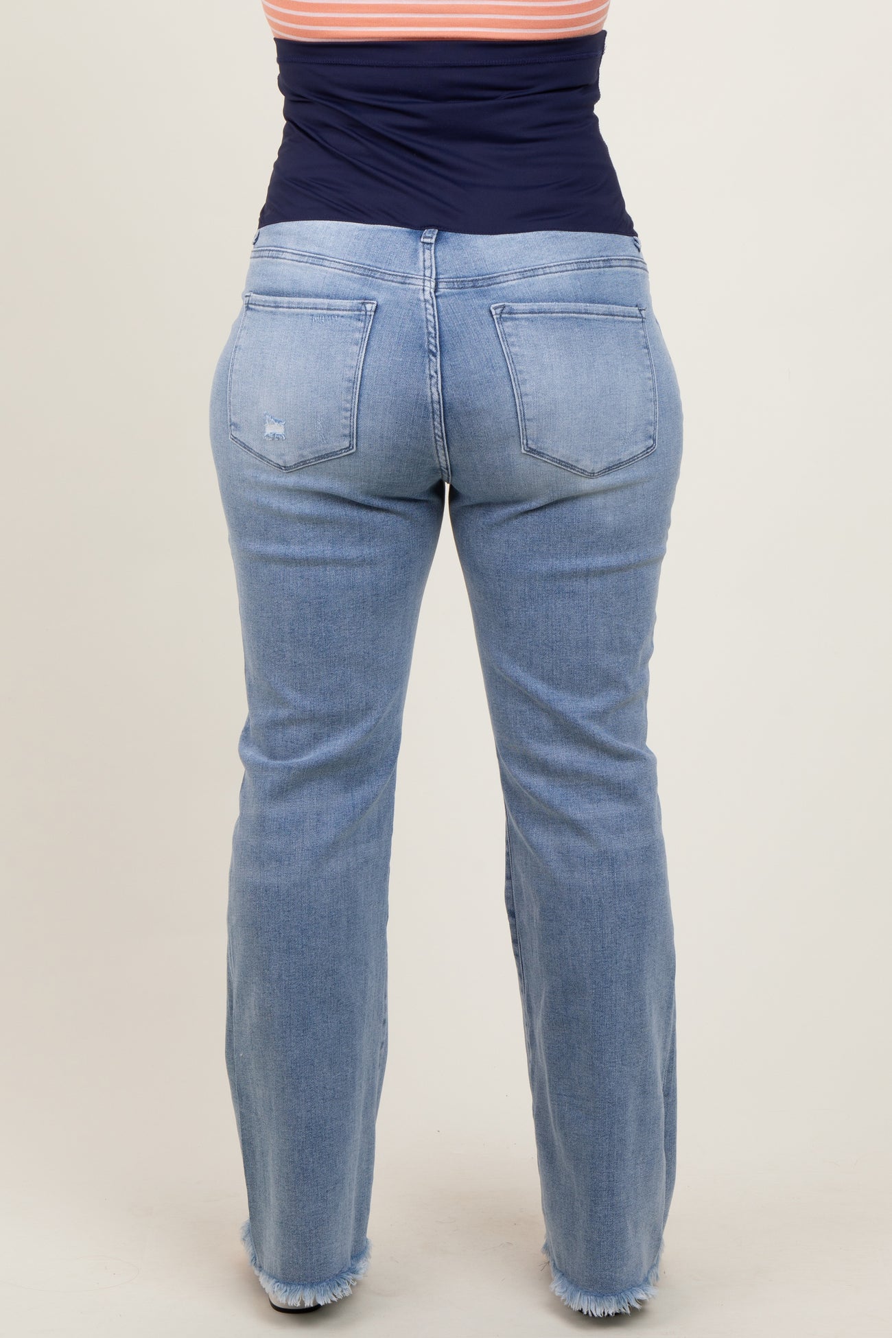 woman wearing light blue maternity plus jeans with a relaxed fit and frayed hem from the back