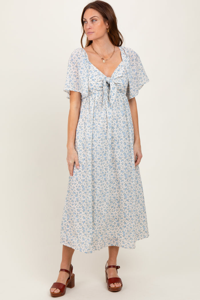 woman wearing a light blue floral maxi dress with a tie front and flutter sleeves
