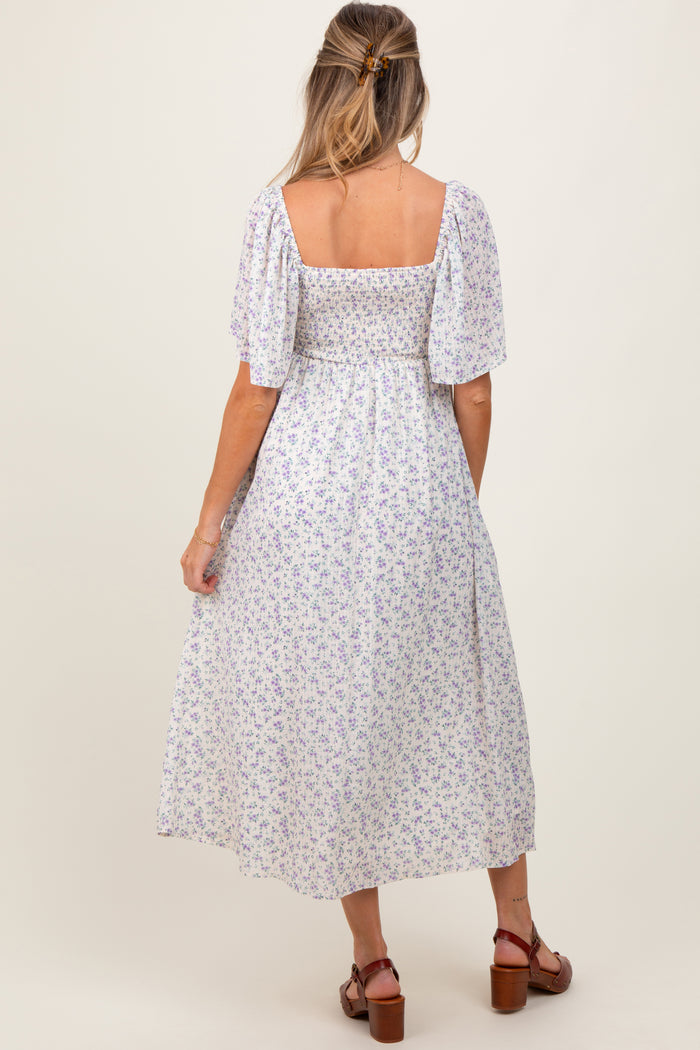 woman wearing a back view of a white floral smocked maternity dress with puff sleeves