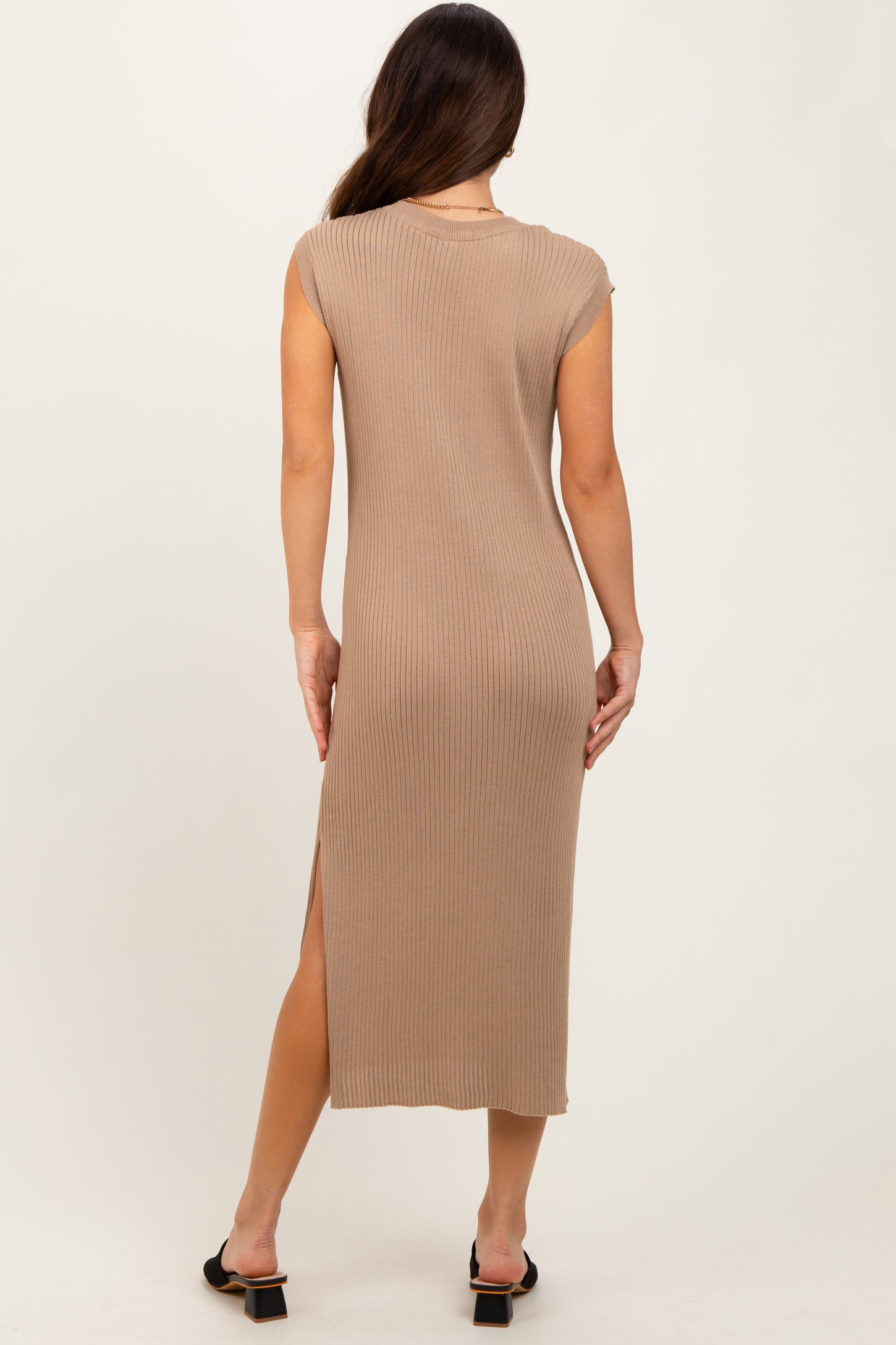 woman wearing a beige ribbed maxi dress with a high slit and cap sleeves, seen from the back