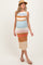 woman wearing a striped maternity dress with a fitted silhouette and a baby bump, paired with a straw hat and sandals