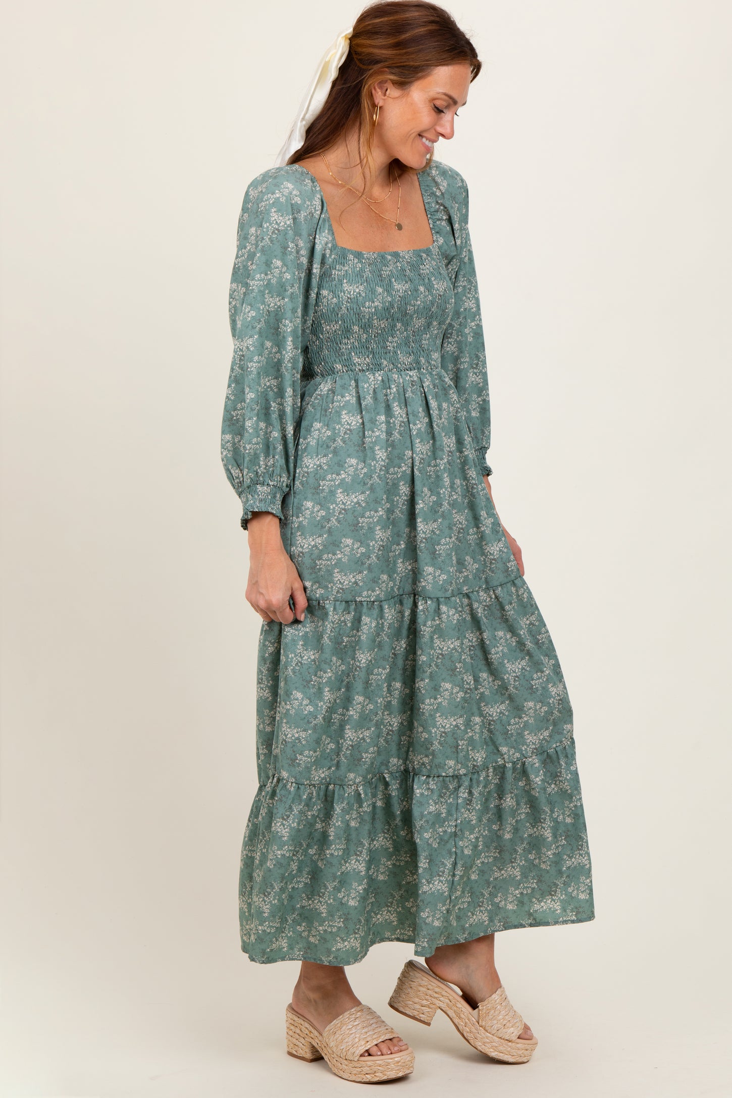 woman wearing a teal floral long sleeve tiered maxi dress with a square neckline and smocked bodice