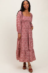 woman wearing a mauve floral long sleeve maxi dress with a square neckline and tiered ruffle hem