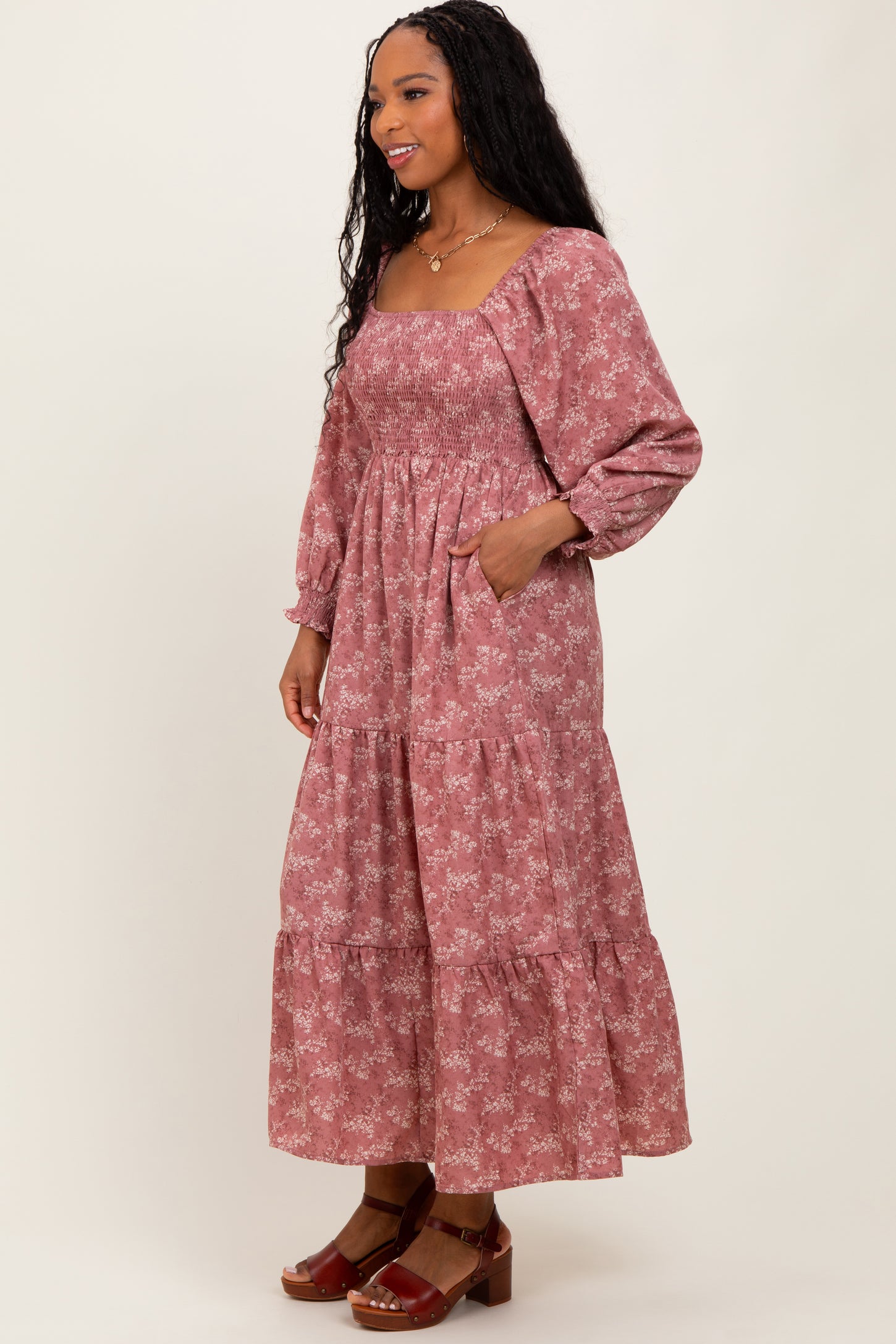 woman wearing a dusty rose floral smocked long sleeve maxi dress with tiered skirt and pockets
