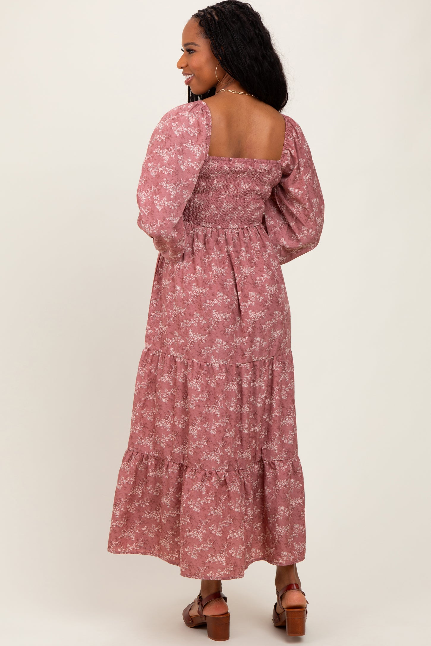 woman wearing a pink floral maxi dress with puff sleeves and tiered skirt, showing the back view