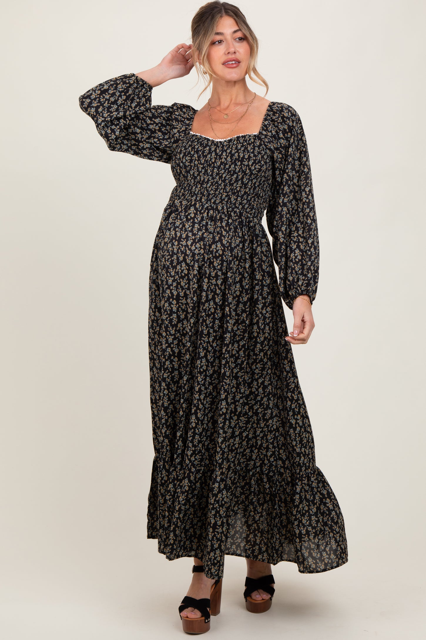 woman wearing a black floral maternity maxi dress with balloon sleeves and a square neckline, showing a baby bump