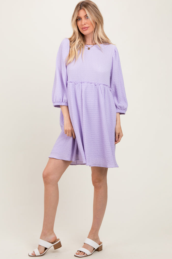 woman wearing a lavender puff sleeve dress with a gathered waist and a relaxed fit, paired with white block heeled sandals