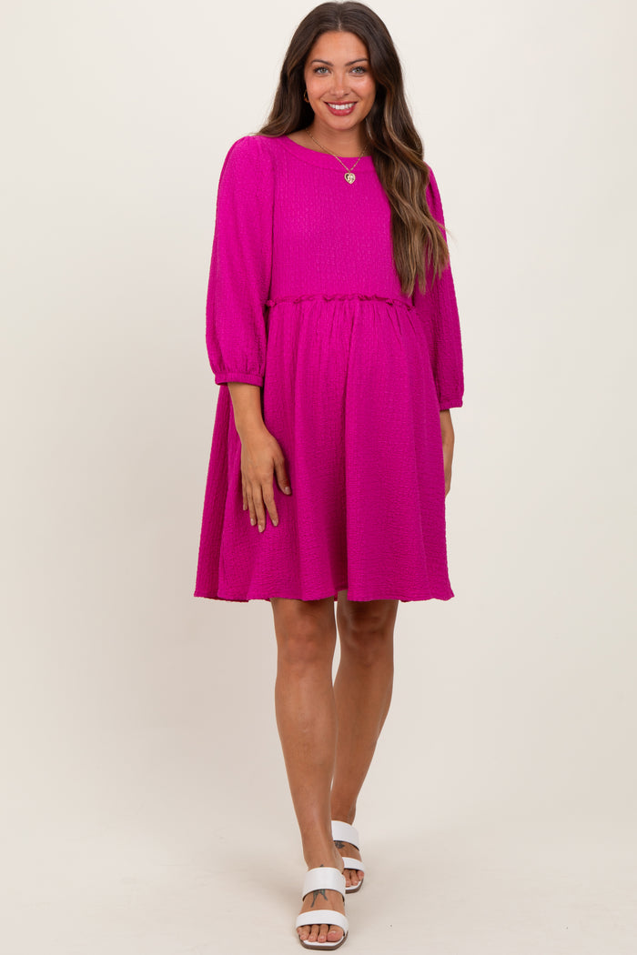 woman wearing a bright pink maternity dress with three-quarter sleeves and a gathered waist, showcasing a baby bump