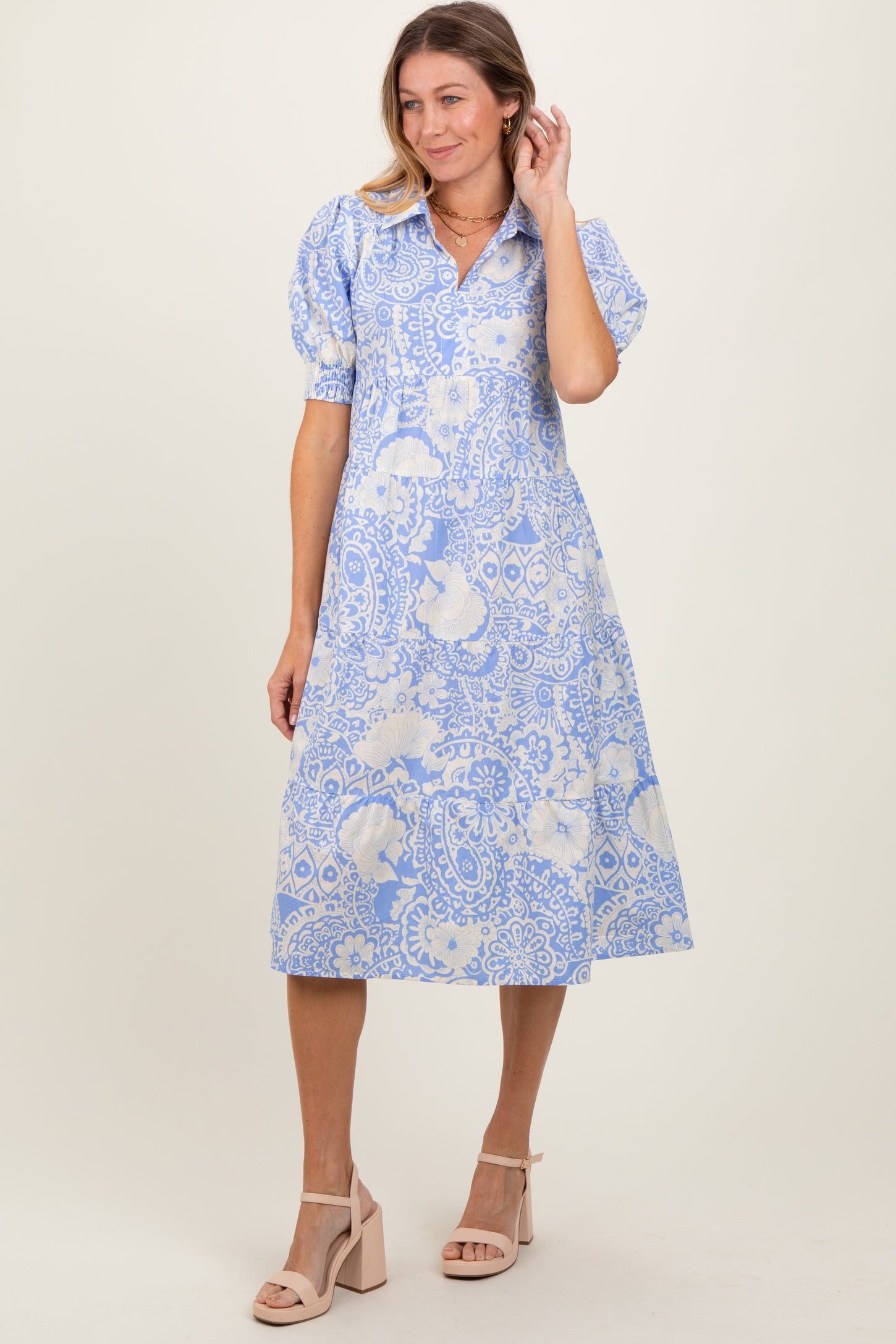 woman wearing a blue and white floral print midi dress with puff sleeves and a collared neckline