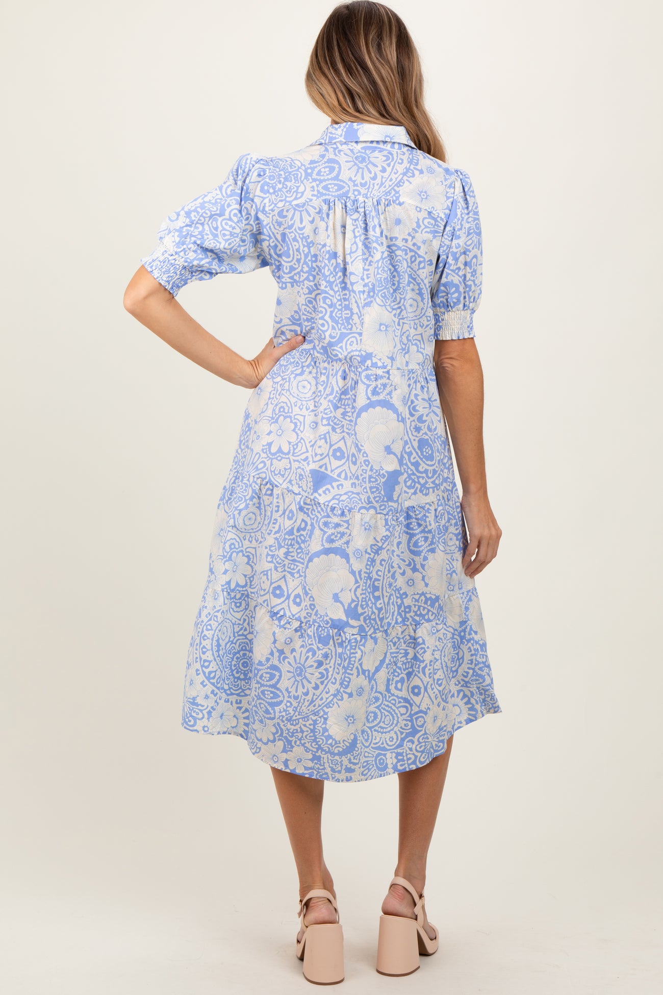 woman wearing a blue and white floral midi dress with puff sleeves, showing the back view