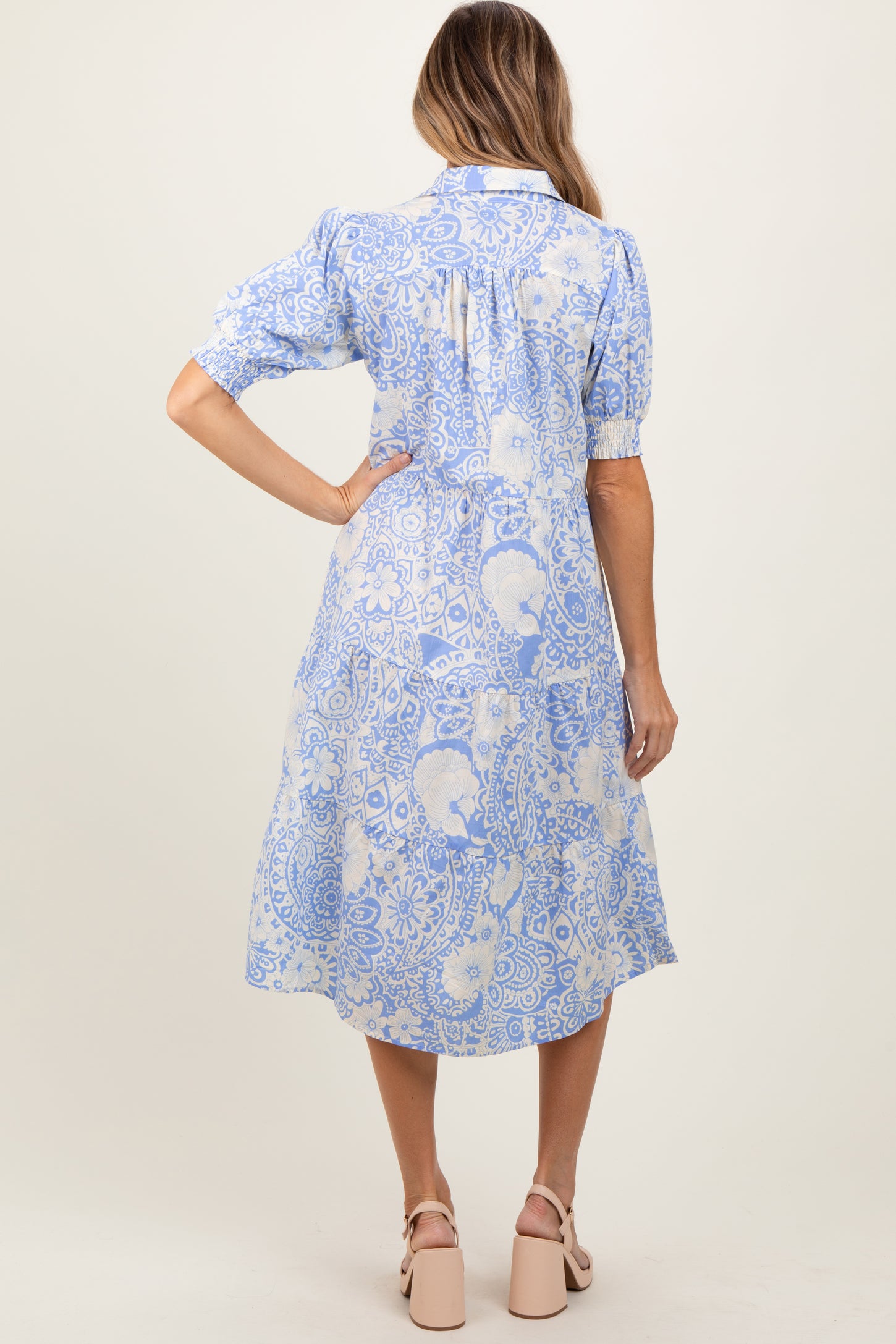 woman wearing a blue and white floral midi dress with puff sleeves, showing the back view