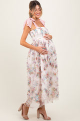 woman wearing a floral maternity dress with a pink tie strap and holding her baby bump