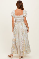 woman wearing a white floral maxi dress with puff sleeves and a smocked bodice, shown from the back