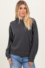 woman wearing a dark gray oversized hoodie with a drawstring and relaxed fit, paired with light blue jeans