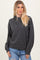 woman wearing a dark gray oversized hoodie with a drawstring and relaxed fit, paired with light blue jeans