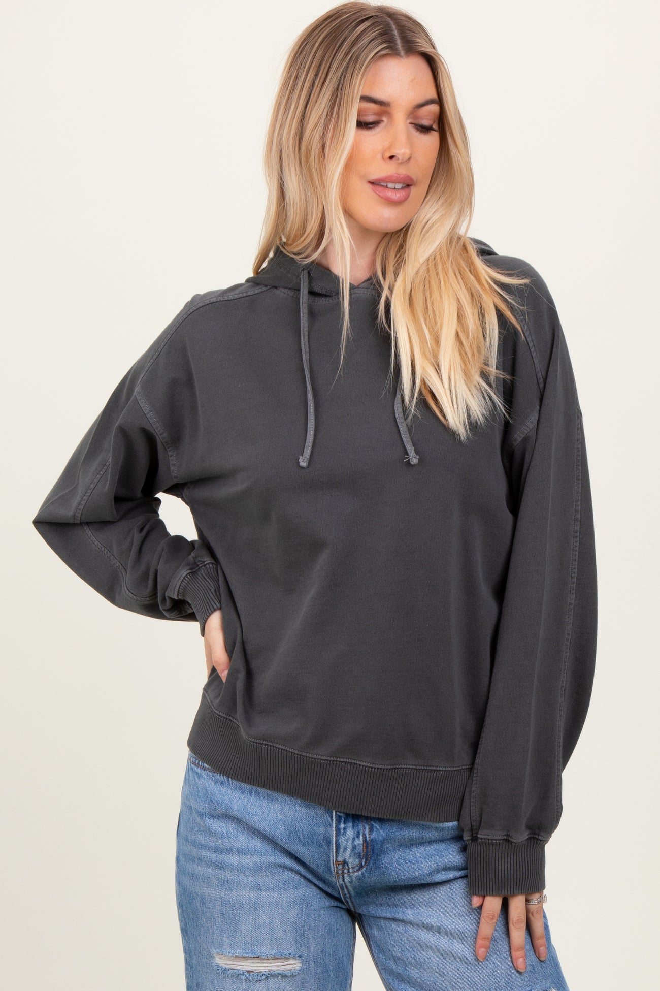 woman wearing a dark gray hooded sweatshirt with a relaxed fit and long sleeves
