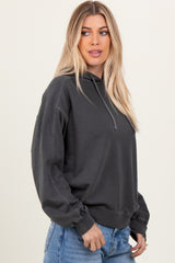 woman wearing a dark gray oversized hoodie with a drawstring and ribbed cuffs, styled with light blue jeans