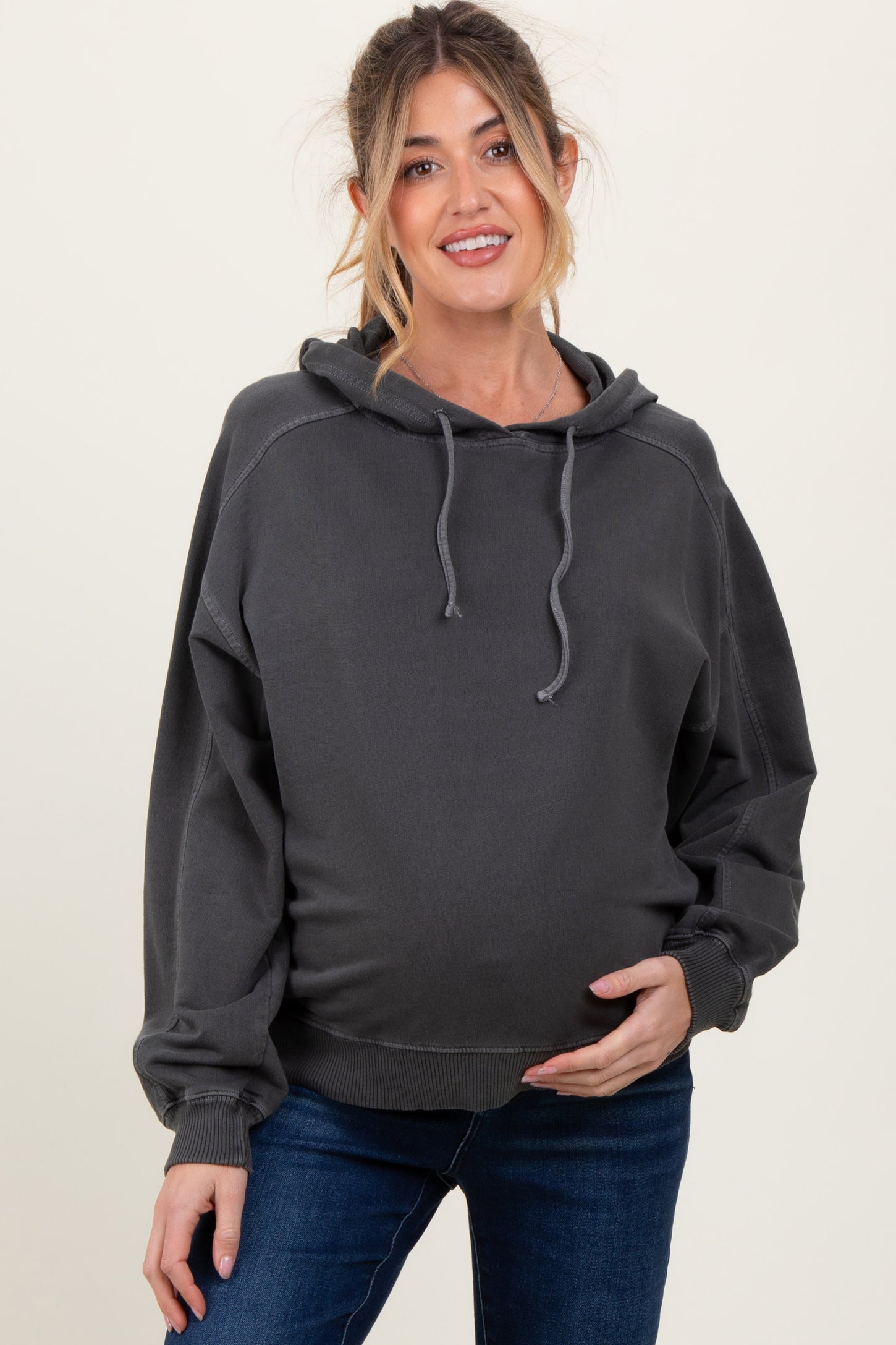 woman wearing a dark gray maternity hoodie with a relaxed fit and a visible baby bump