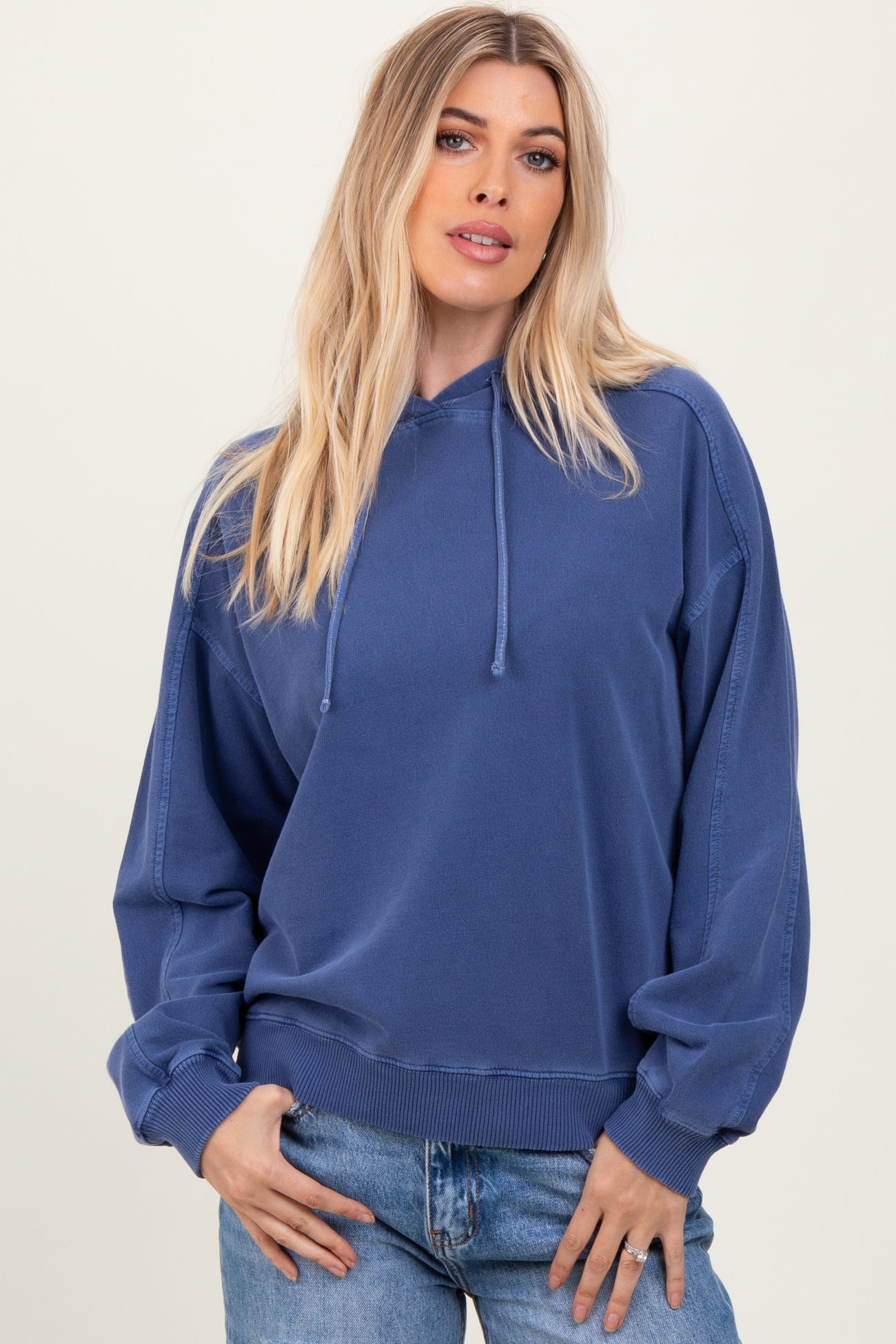 woman wearing a mauve oversized hoodie with a drawstring hood and relaxed fit, styled with blue jeans