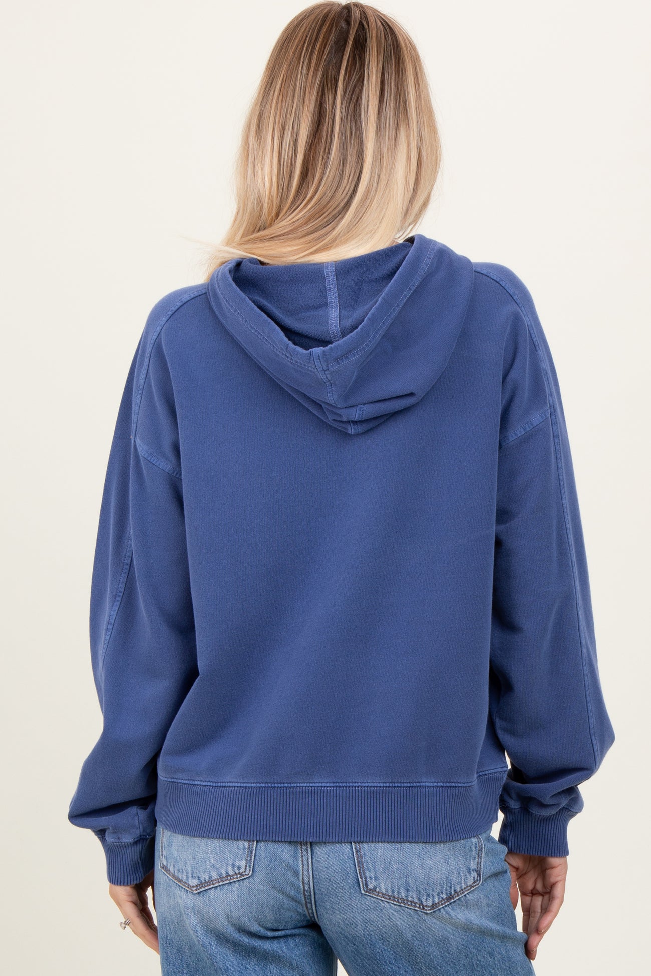 woman wearing a navy blue oversized hoodie with a hood and ribbed cuffs, showing the back view