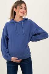 woman wearing a blue maternity hoodie with a relaxed fit, holding her baby bump