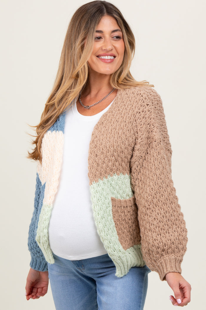 woman wearing a multi-colored knitted maternity cardigan and showing her baby bump