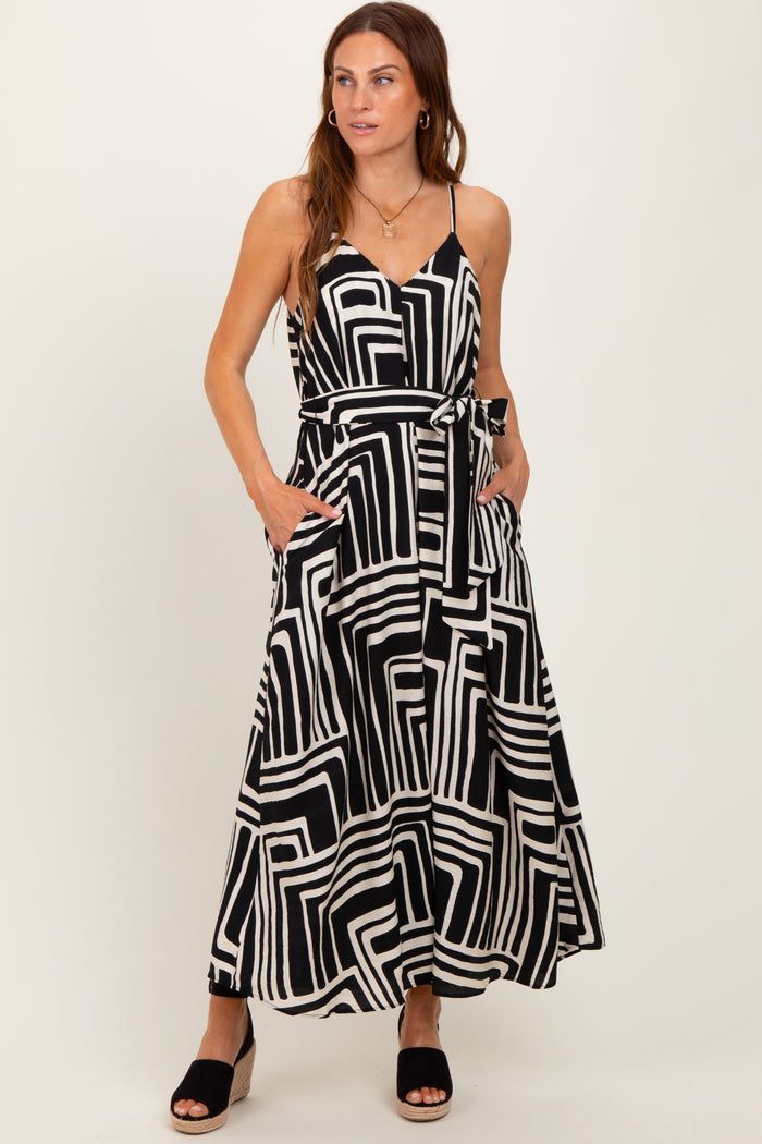 woman wearing a black and white geometric print maxi dress with pockets and a tie waist