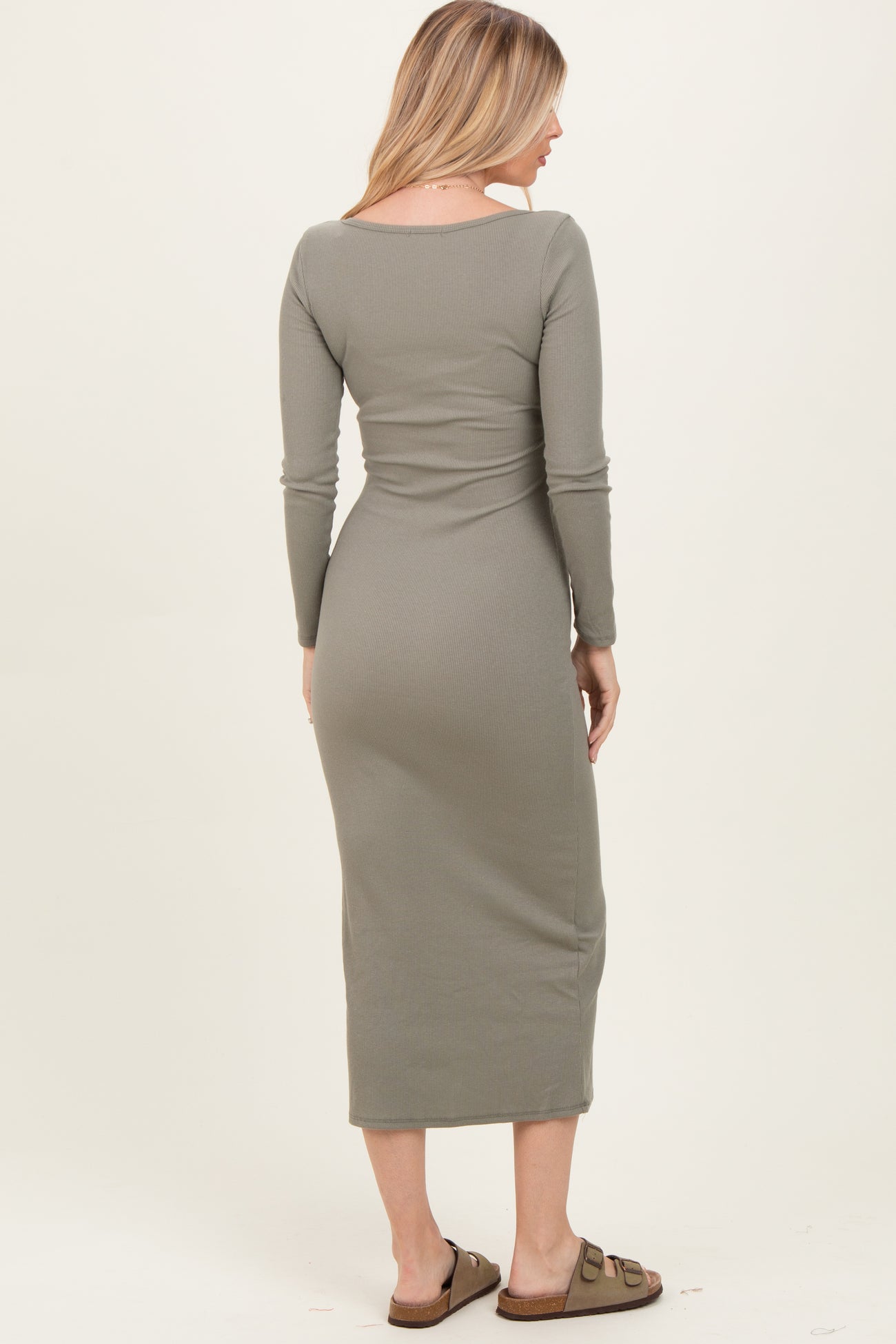 woman wearing a grey ribbed long sleeve maxi dress, seen from the back, with a fitted silhouette and sandals