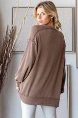woman wearing a brown ribbed oversized sweater viewed from the back, styled with light-colored pants
