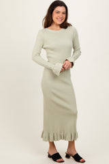 woman wearing a light green ribbed knit midi dress with flared sleeves and ruffle hem, styled with black slide sandals